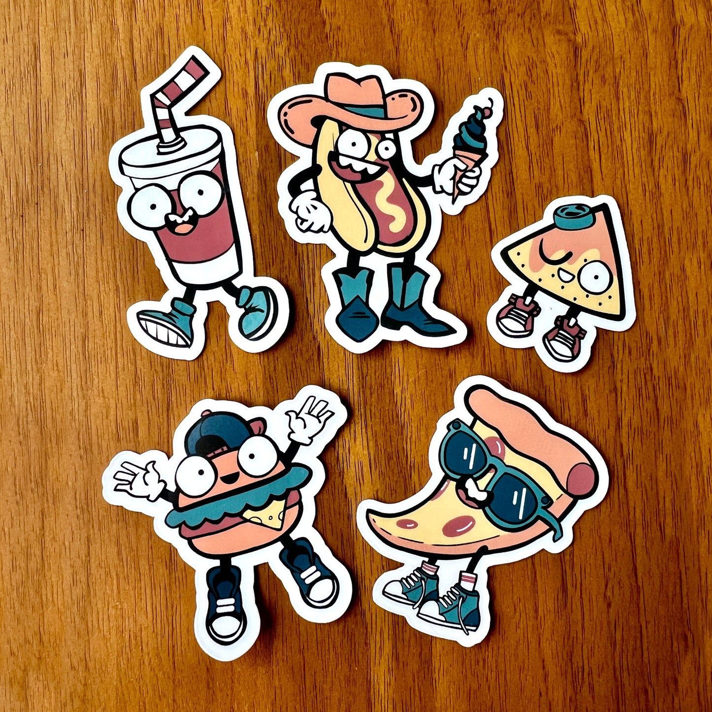 Five cartoon-style food stickers on a wooden surface