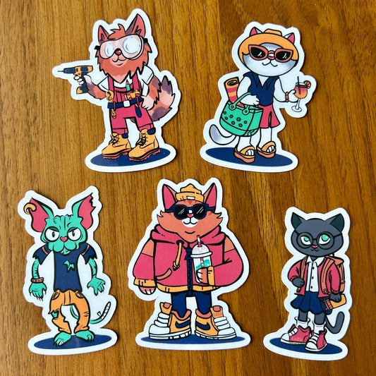 Five cat cartoon character stickers on a wooden surface