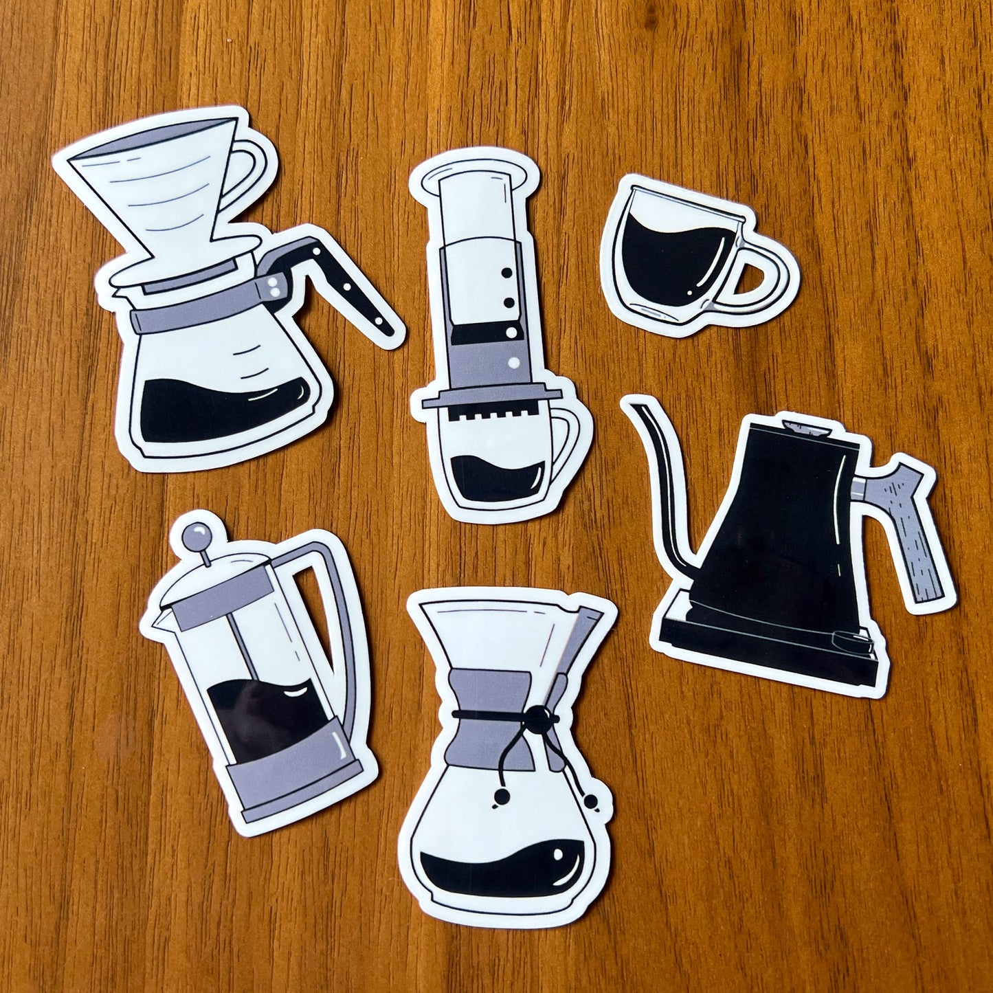 Set of six coffee-themed stickers on a wooden surface